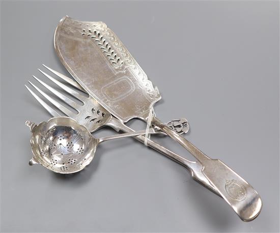 A George III silver fish slice a later matching serving fork and a silver tea strainer.